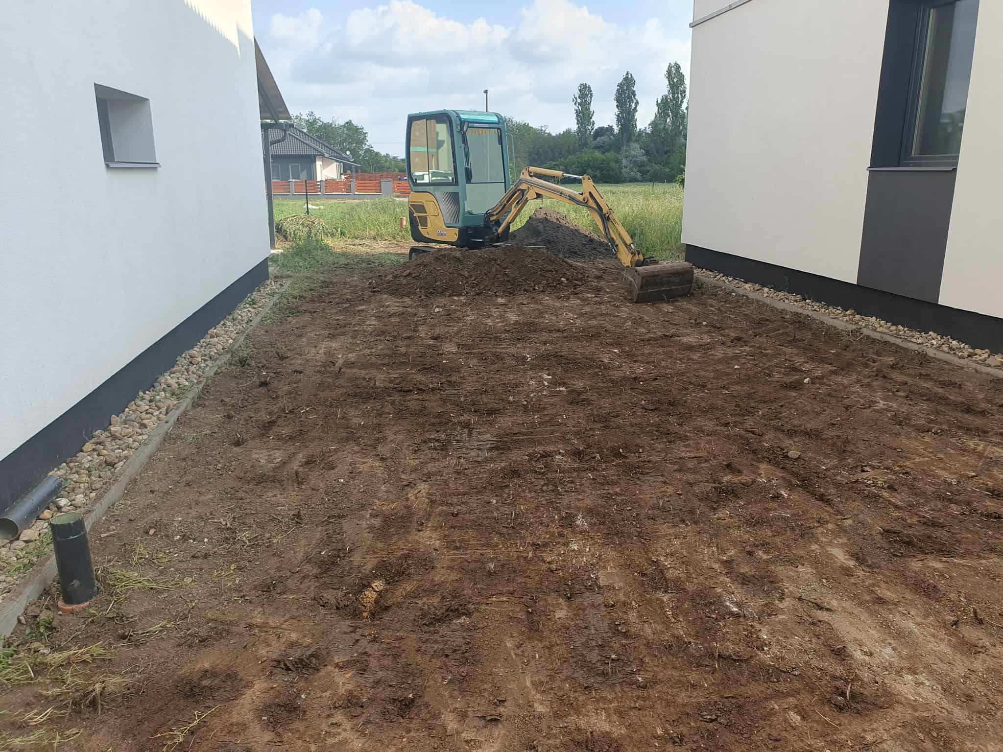 Munkagép terület-előkészítést végez két épület között